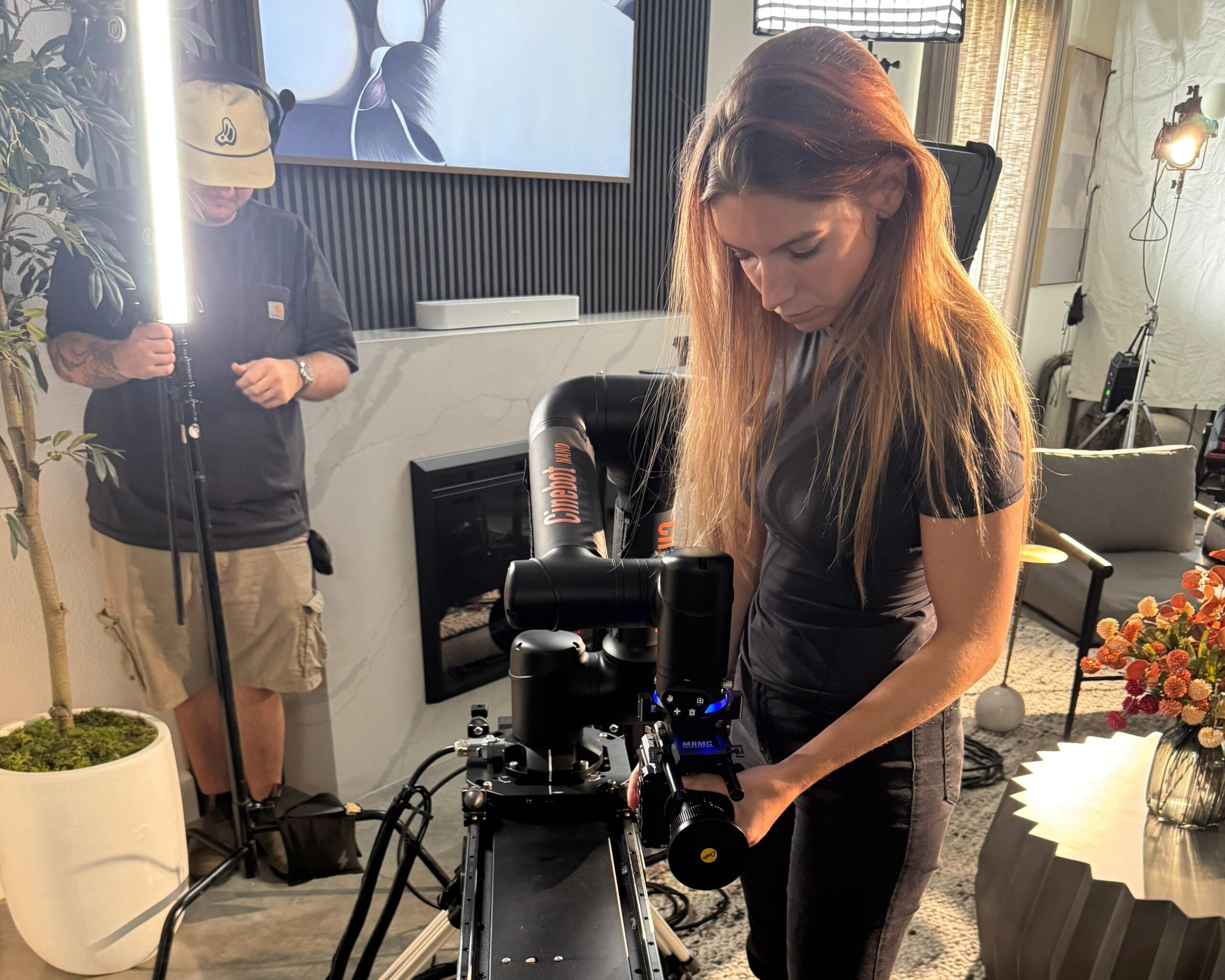 Videographer Rose setting up the Cinebot Nano on its track while man adjusts lighting in the background