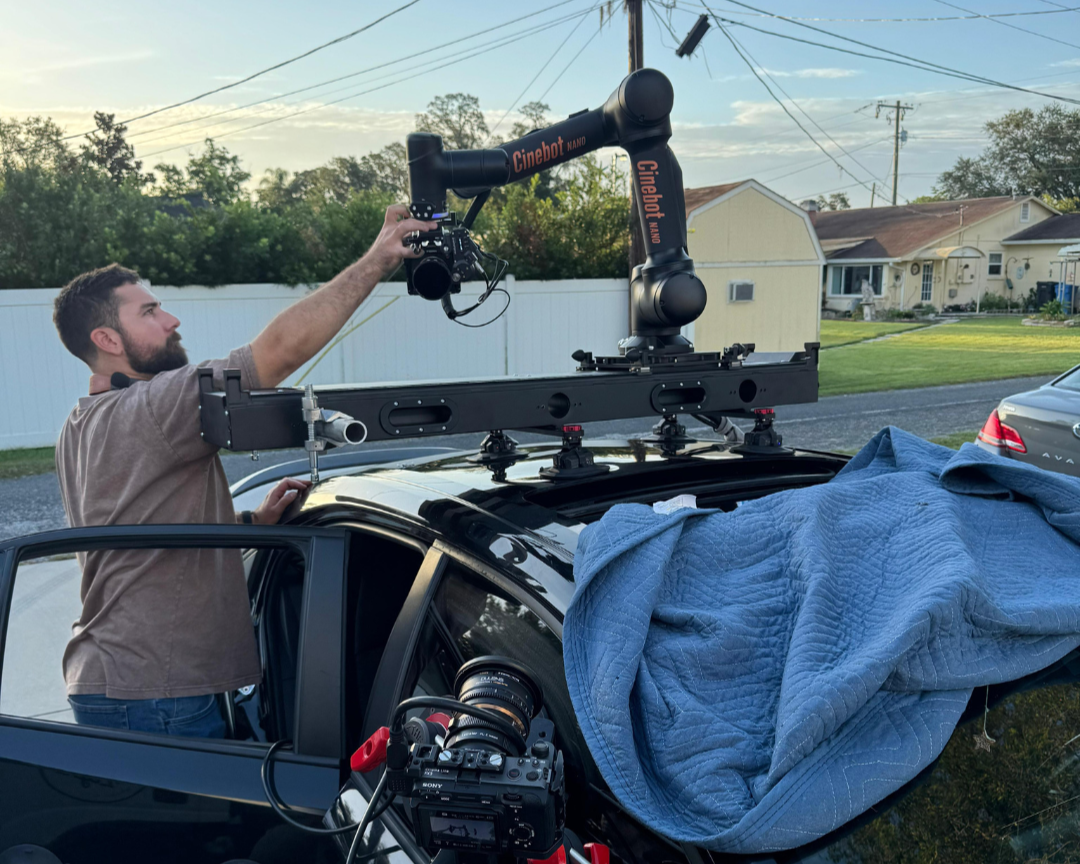 Cinebot Nano camera robot being setup and mounted onto a vehicle by a crew member.
